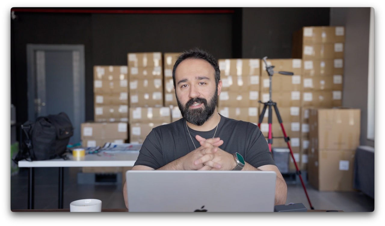 Onur presenting from a warehouse surrounded by product inventory